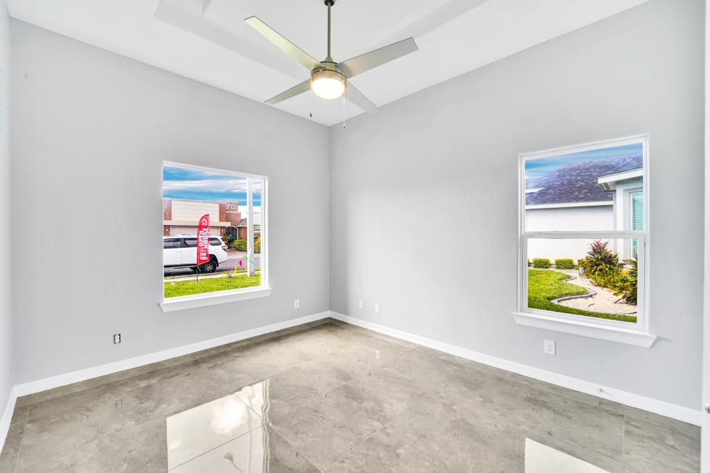 Empty bedroom with two windows, a ceiling fan and polished tile flooring