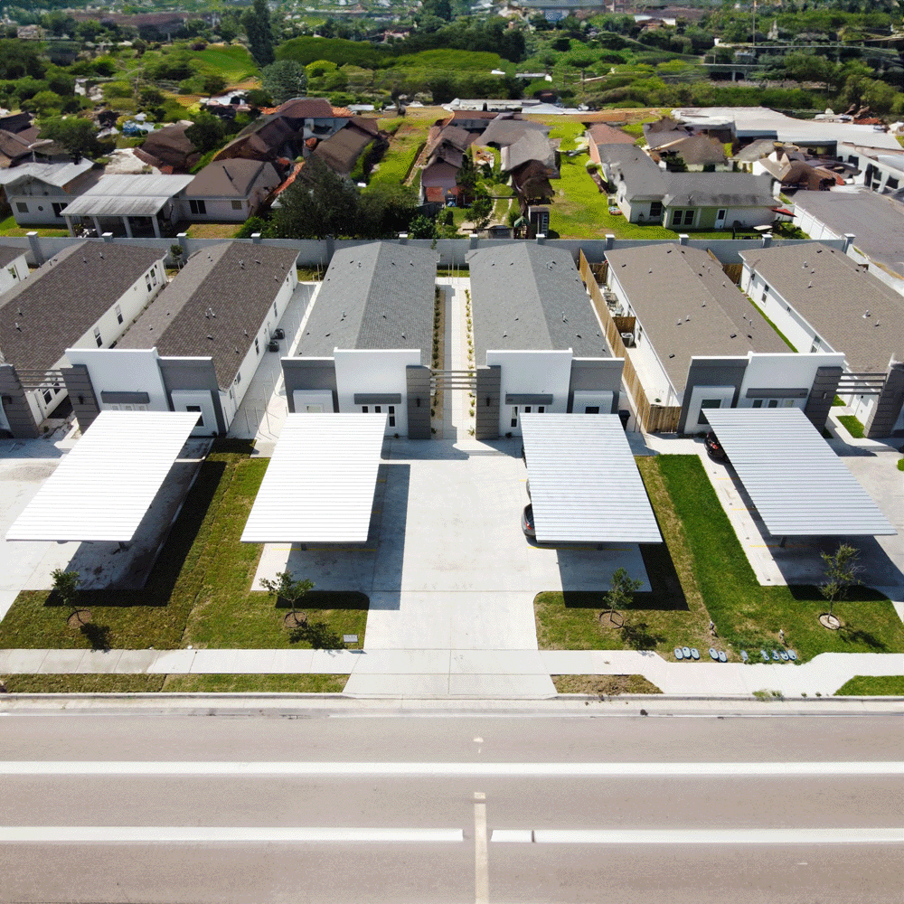 Aerial view of a completed townhome row with carports, seen from the street