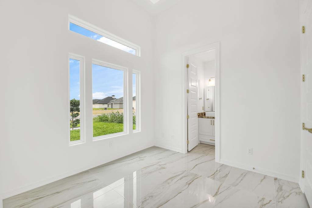 Bright room with a transom window opening through to an ensuite bathroom, marble-look floors throughout